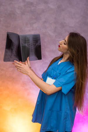 Pensive young doctor examining x-ray and making diagnosis. Medical concept