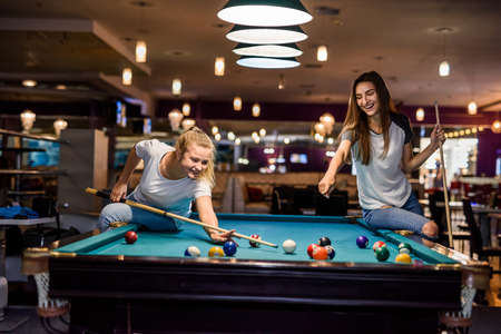 Happy and excited women playing billiard together