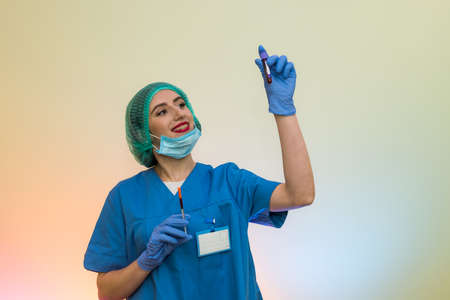 Doctor with syringe and red test tube posing in hospitalの写真素材