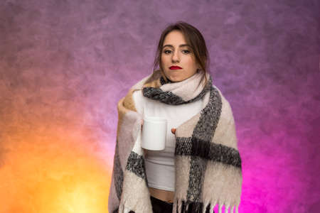 Sick woman with hot cup of tea in warm plaid. Illness and medicine conceptの写真素材