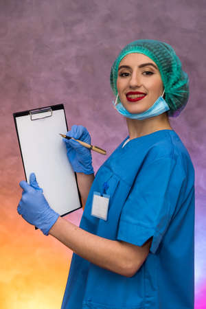 Doctor holding clipboard with pen. Pretty woman in medical form smilingの写真素材
