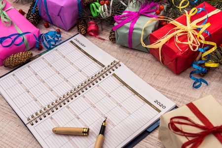 Notepad with pen and colorful gift boxes on wooden table. Celebration and presentsの写真素材