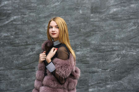 Stylish woman in fur coat posing outdoors on city street. Fashion conceptの写真素材