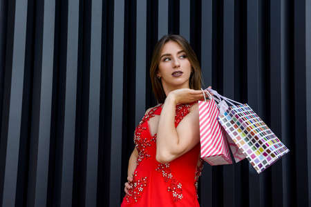 Pretty woman with in red dress holding gift bags. New year and Christmas gifts concept