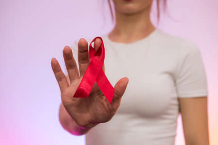 World company of AIDS day. Red ribbon on human hand close up