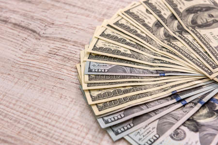 Dollar banknotes in fan on wooden table close up