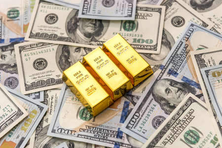 Gold bullion at american dollar banknotes close up