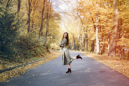 Autumn colors. Beautiful woman in coat posing in forest on roadsideの写真素材