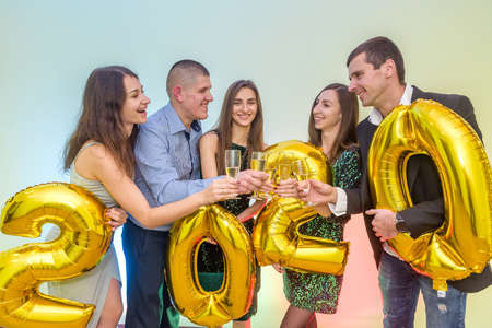 Happy company with champagne glasses celebrating new 2020 year