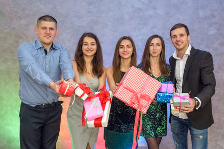 Happy colleagues with present boxes posing on abstract background