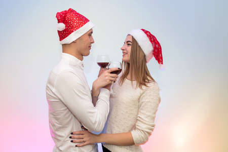 Happy, young couple with wine glasses and santa hats celebrating St. Valentine's dayの写真素材