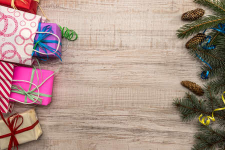 Christmas presents concept. Fir branches with cones and colorful gift boxes on table