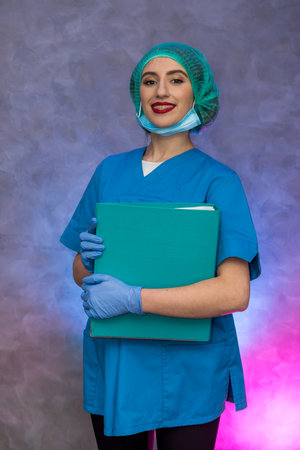 Smiling medical worker holding big folder. Woman in medical uniform posing in hospitalの写真素材