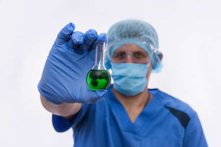 young male lab assistant examining green liquid in test tube