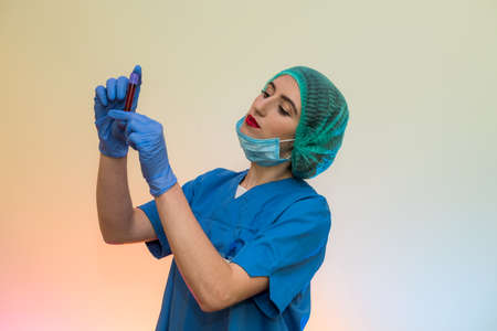 Medical worker with test tubes with blood pose in laboratory. Beautiful woman in protective uniform
