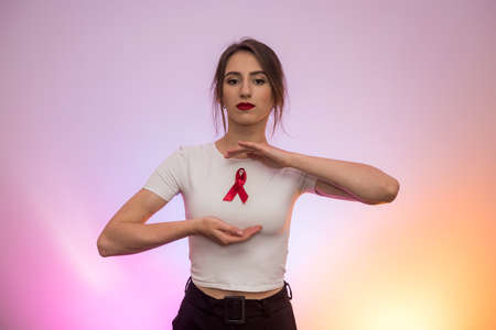 AIDS concept. Woman holding red ribbon in hands close up