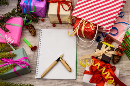 Notepad with pen and colorful gift boxes on wooden table. Celebration and presentsの写真素材