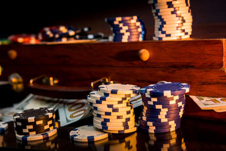 Gambling background. Colorful poker chips on playing table with wooden box for themの写真素材