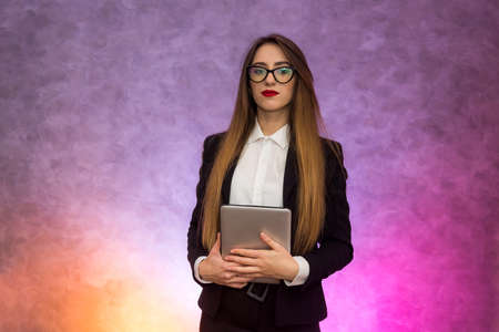 Cute woman in glasses using tablet on abstract background. Business concept