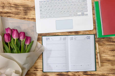 Office desk and bouquet of tulips top view