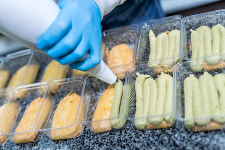 Colorful and delicious pistachio dessert in plastic package on table in factory. Food industrial...
