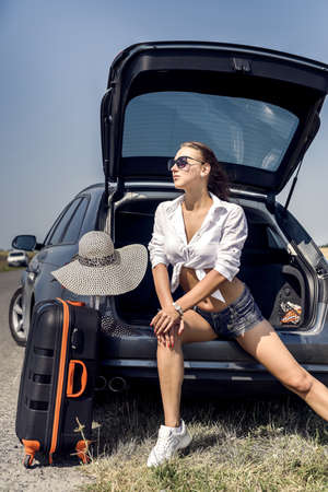 sexy beautiful european model in summer vacation and sunglasses posing in luxurious auto in nature in the summer landscape.の写真素材