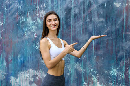 Young woman in sportswear gesturing on gray wallの写真素材