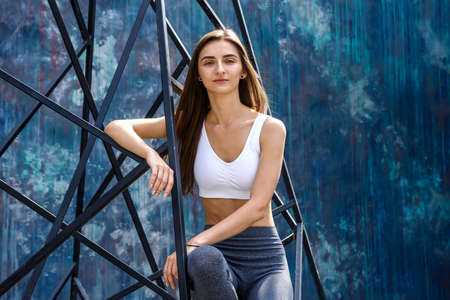 Sportive and young woman posing with urban constructions on the street. Woman and city