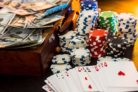 Gambling Concepts. Betting is a gamble for investors. Case full of chips, dollars and playing cards on a black backgroundの写真素材