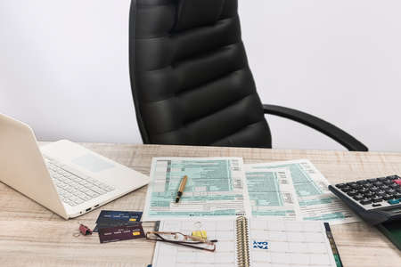 Accountant office - 1040 US tax forms April 15 of the deadline time, laptop, money and pen