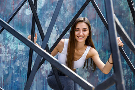 Sportive and young woman posing with urban constructions on the street. Woman and city