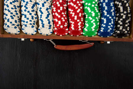 Many poker chips in a suitcase isolated on a black background. Poker