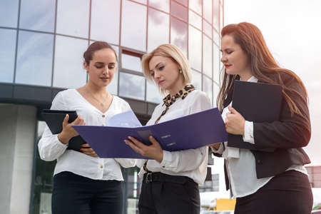 Three managers with folders posing outside office buildingの写真素材