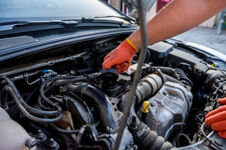 Human hands examining car engine in protective gloves close upの写真素材