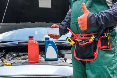 Car service advertising. Mechanic standing near car showing thumb up. Car with opened hoodの写真素材
