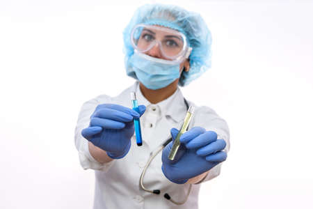 Chemist working in lab. Beautiful woman with test tubes wearing protective uniform and making experimentsの写真素材