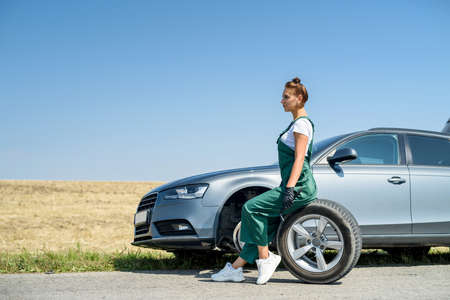 woman working with broken wheel of her car, waiting for helpの写真素材