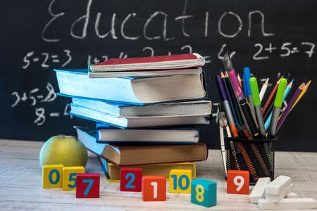 Green apple with stack of books and writing supplies against blackboard. Education conceptの写真素材
