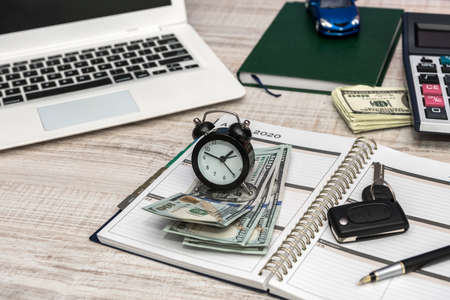 Business - car key, laptop money and notepad on desk.