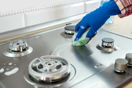 Woman with sponge and rubber protective glove used to wipe down an oven range topの写真素材