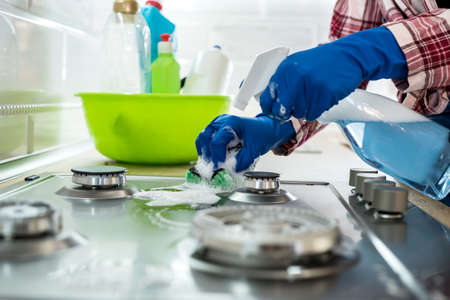 young woman cleaning in rubber gloves and sponge in the kitchen at home.の写真素材