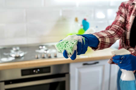 young woman cleaning in rubber gloves and sponge in the kitchen at home.の写真素材