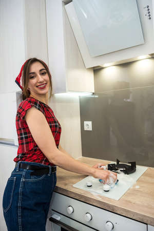 Housewife washing the gas stove with detergent in the kitchen. House cleaning.の写真素材