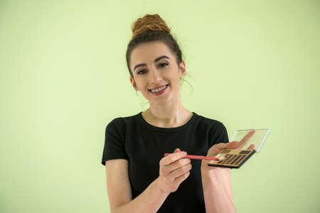 Attractive girl with makeup brushes isolated on green. concept of beauty and healthの写真素材