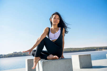 beautiful girl relaxing after morning gymnastics by the lake. health and beauty concept