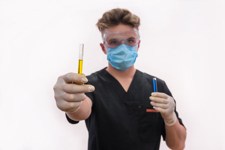 Chemist in protective uniform holding flask and test tube with minerals isolated on white. Science and experiment conceptの写真素材