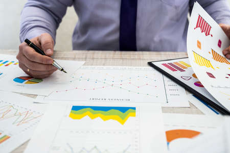 A business male analyzes revenue and graphs at office. Business analysis and strategy concept. Businessman develop a business project and analyze market information, photosession from Aboveの写真素材