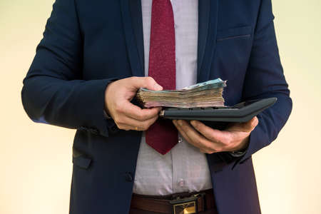 businessman in suit hold calculator and lot of ukraine money, UAH, grivnya, isolated on greenの写真素材