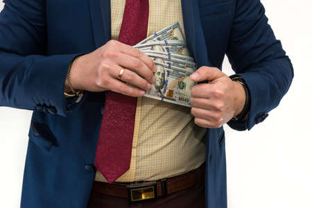 Businessman gets bribed and hides dollars in jacket pocket. Men's hands hold money, illegal wealth. Corruptionの写真素材