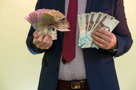 Male hands holding stack of ukrainian hryvnia banknotes isolated on green. Hryvnia new 1000 500 and 200 uah banknotes. Save money conceptの写真素材